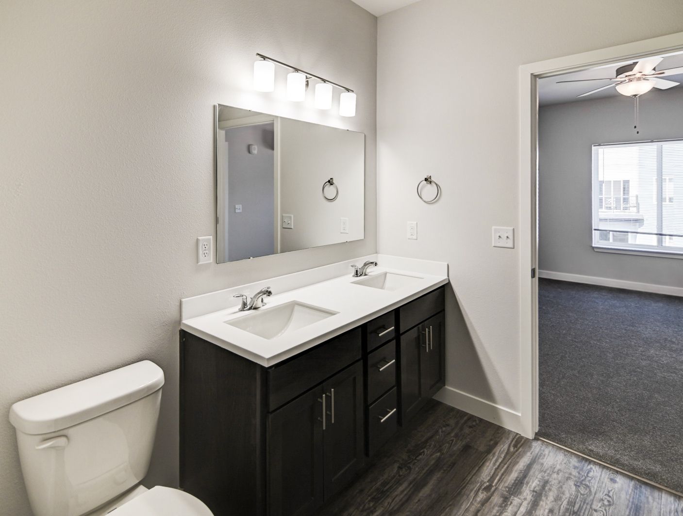 A bathroom with two sinks , a toilet and a mirror.