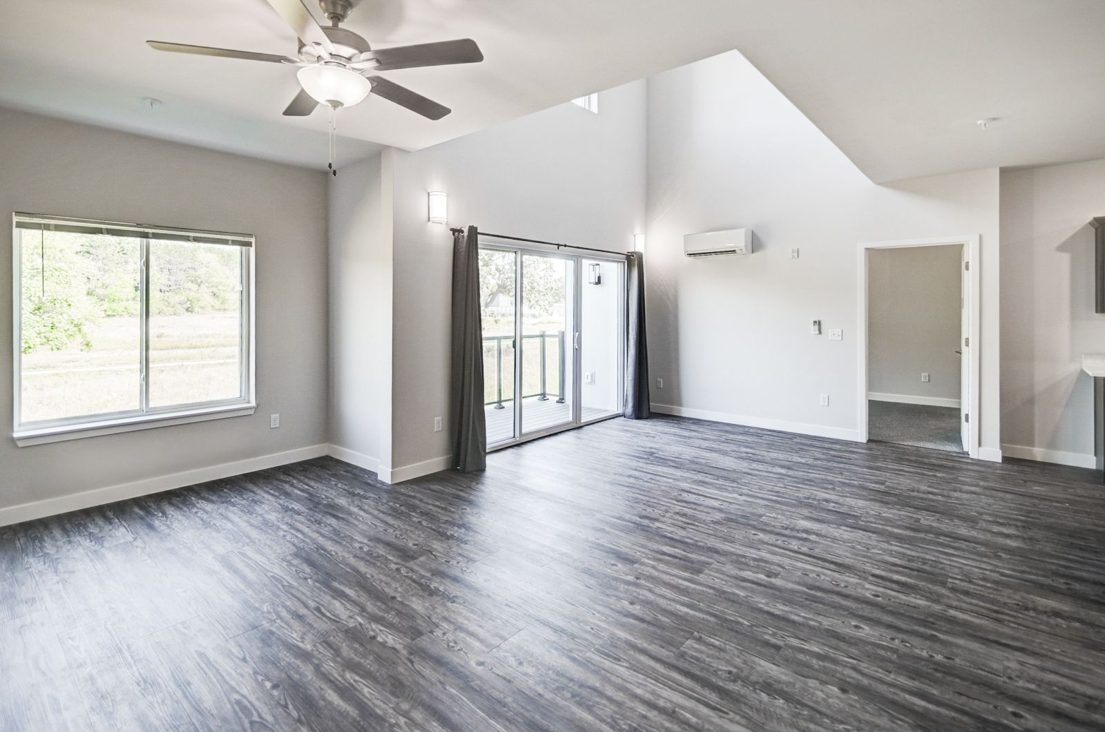 An empty living room with hardwood floors and a ceiling fan.