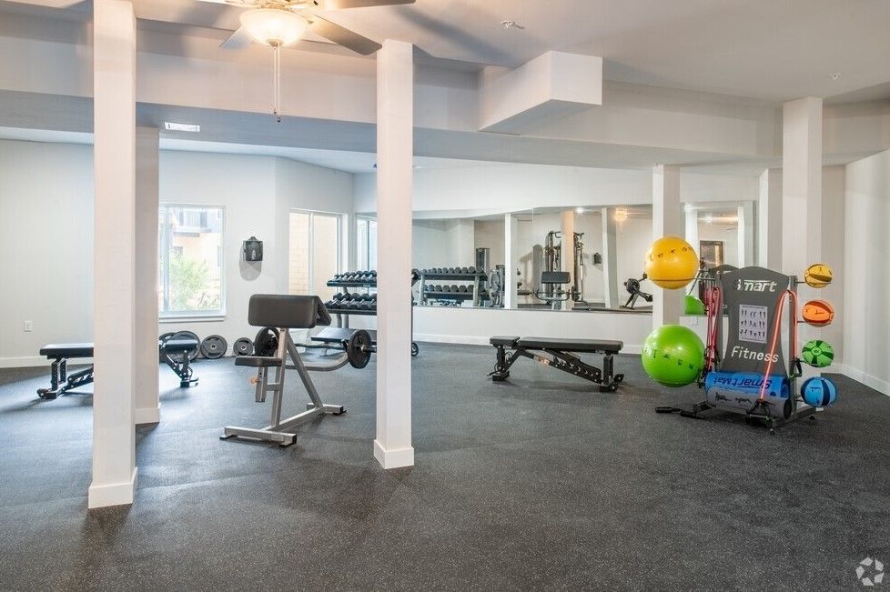 A large gym with a lot of equipment and a ceiling fan.