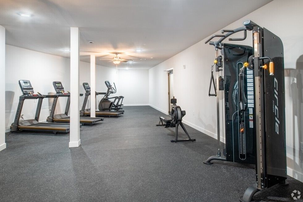 A gym with treadmills , exercise bikes , and a rowing machine.