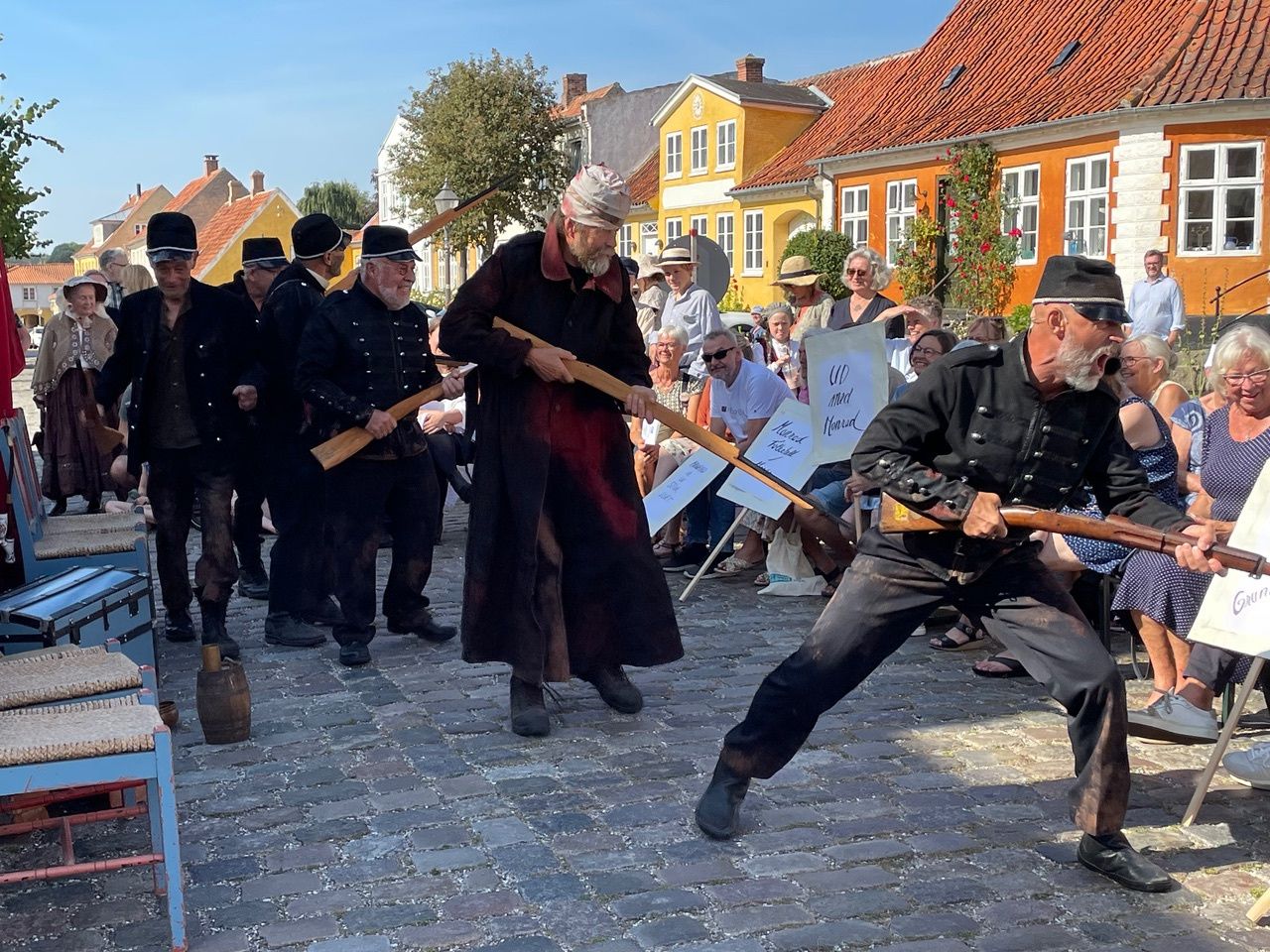 En gruppe mænd der optræder foran mennesker der sidder ned på torvet i Præstø