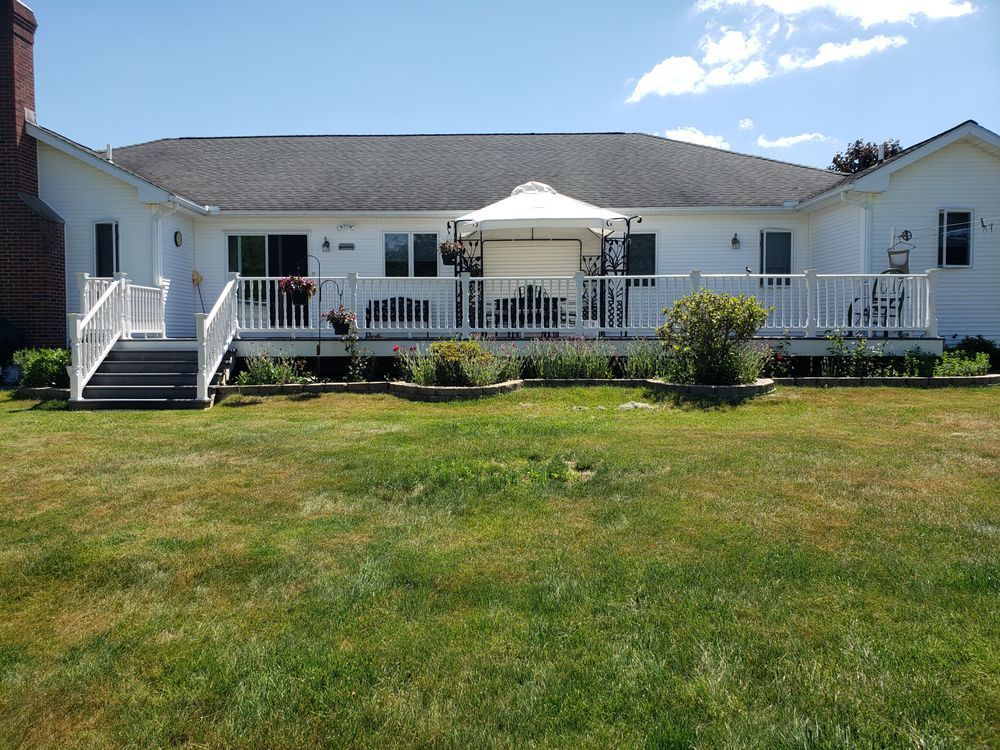White house with a deck and gazebo on a sunny lawn, viewed from the yard