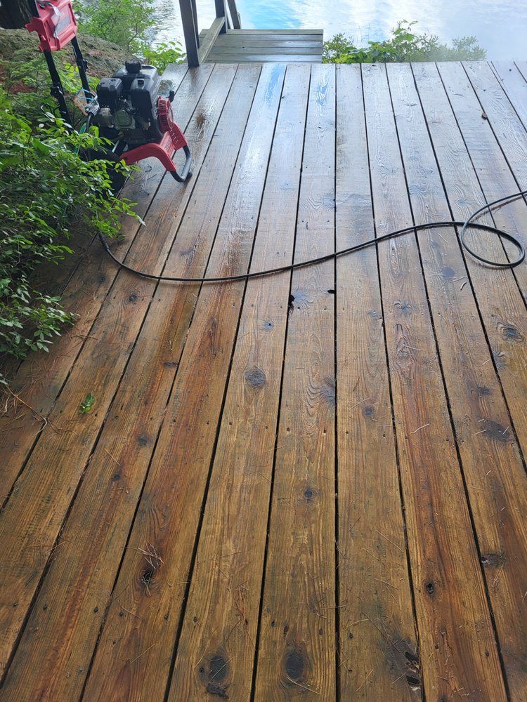 Wet wooden deck with a black hose and a red pressure washer near the top left.