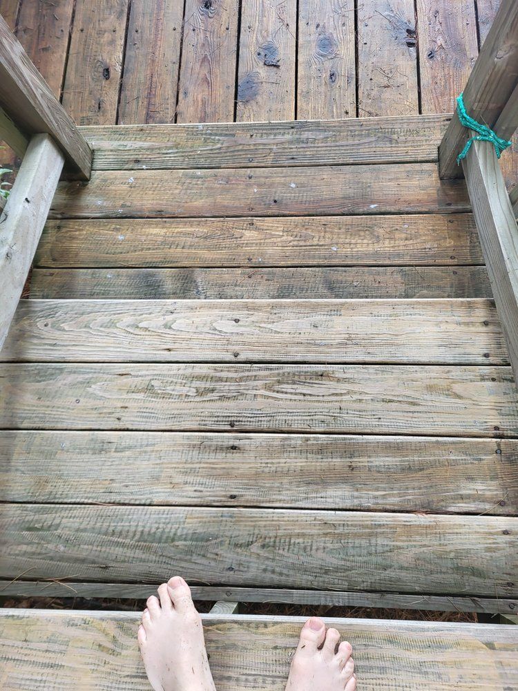 Looking down a weathered wooden dock with bare feet at the bottom edge