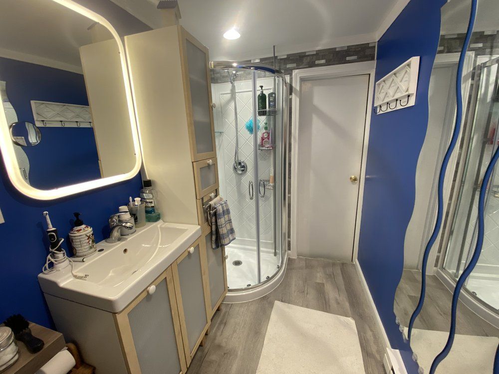 Modern blue-and-white bathroom with sink, shower, and gray floor mat