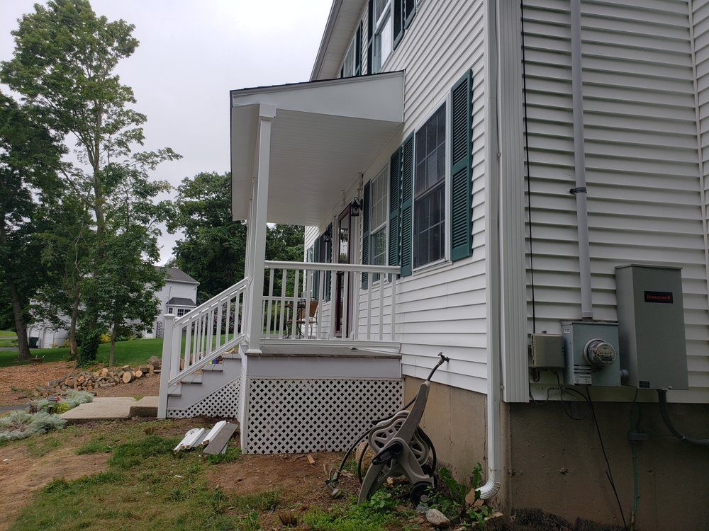 White house front porch with steps, lattice skirting, and a bicycle beside the siding