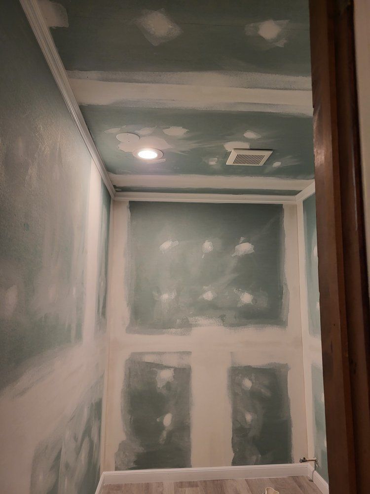 Unfinished drywall room with taped seams, ceiling light, and vent opening