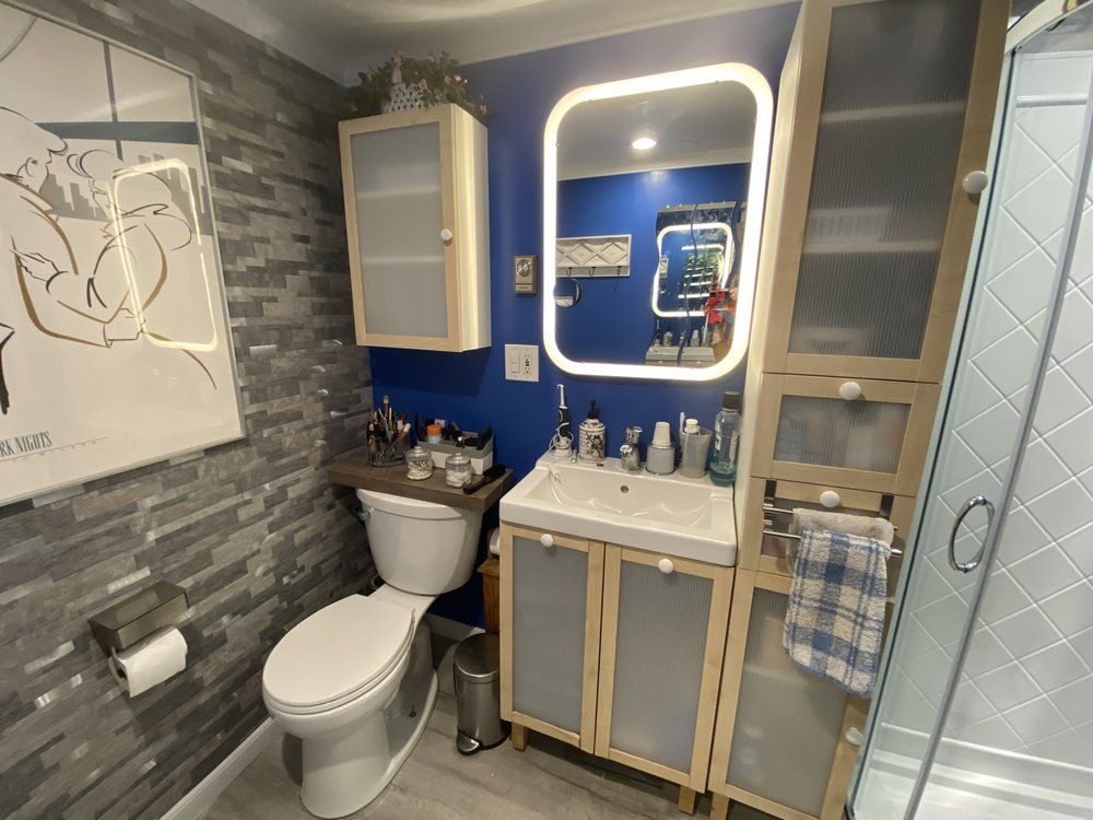 Small bathroom with vanity, toilet, tiled walls, blue accent wall, and glass shower door