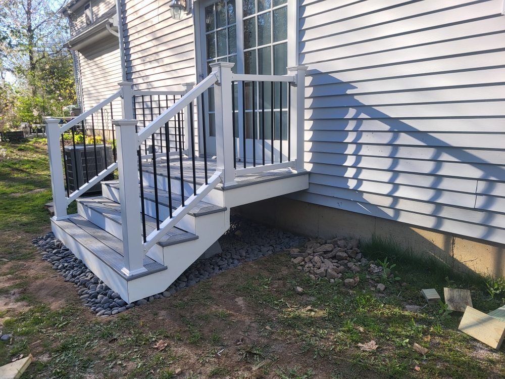 White front steps with metal railings leading to a small porch beside a gray-sided house.