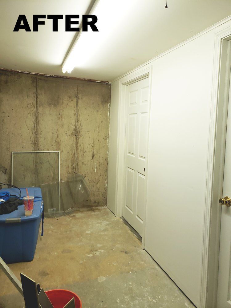 Unfinished basement with exposed concrete wall, white doors, fluorescent light, and a blue storage bin.