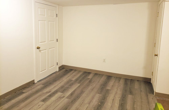 Empty beige room with white doors and gray wood-look flooring
