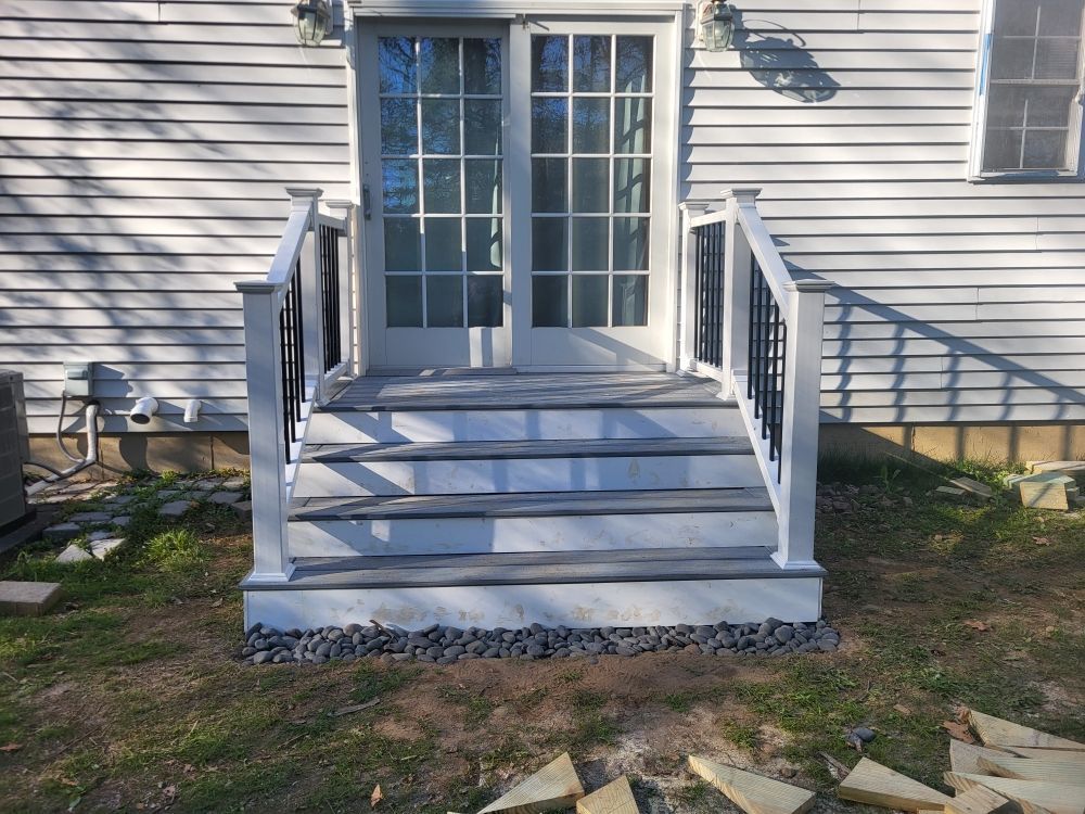 Front porch stairs with white railings leading to French doors on a house exterior.
