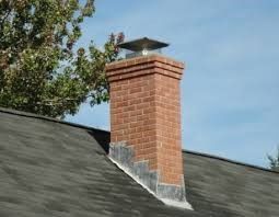 A brick chimney is on the roof of a house.