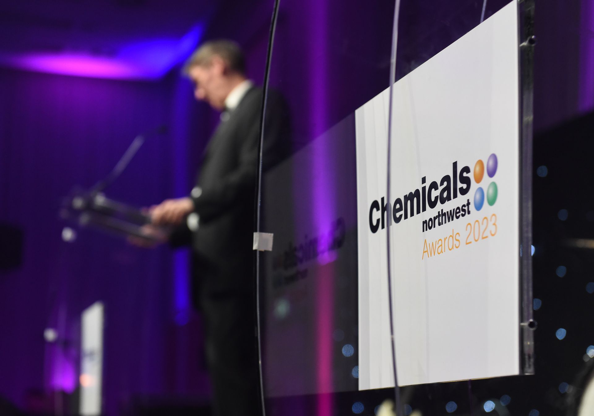 podium displaying 'Chemicals Northwest awards 2023' in focus, with CNW CEO giving the welcome speech, blurred in the background