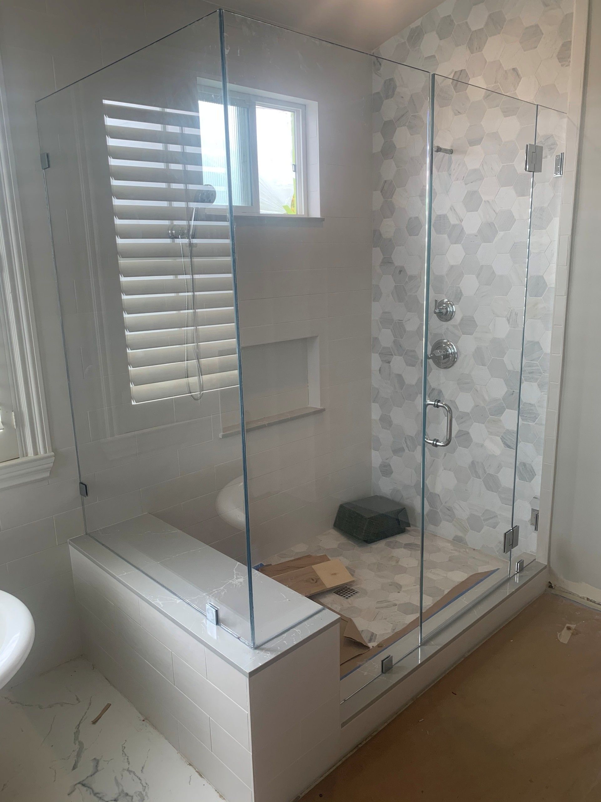 Glass shower enclosure with white tile and window.