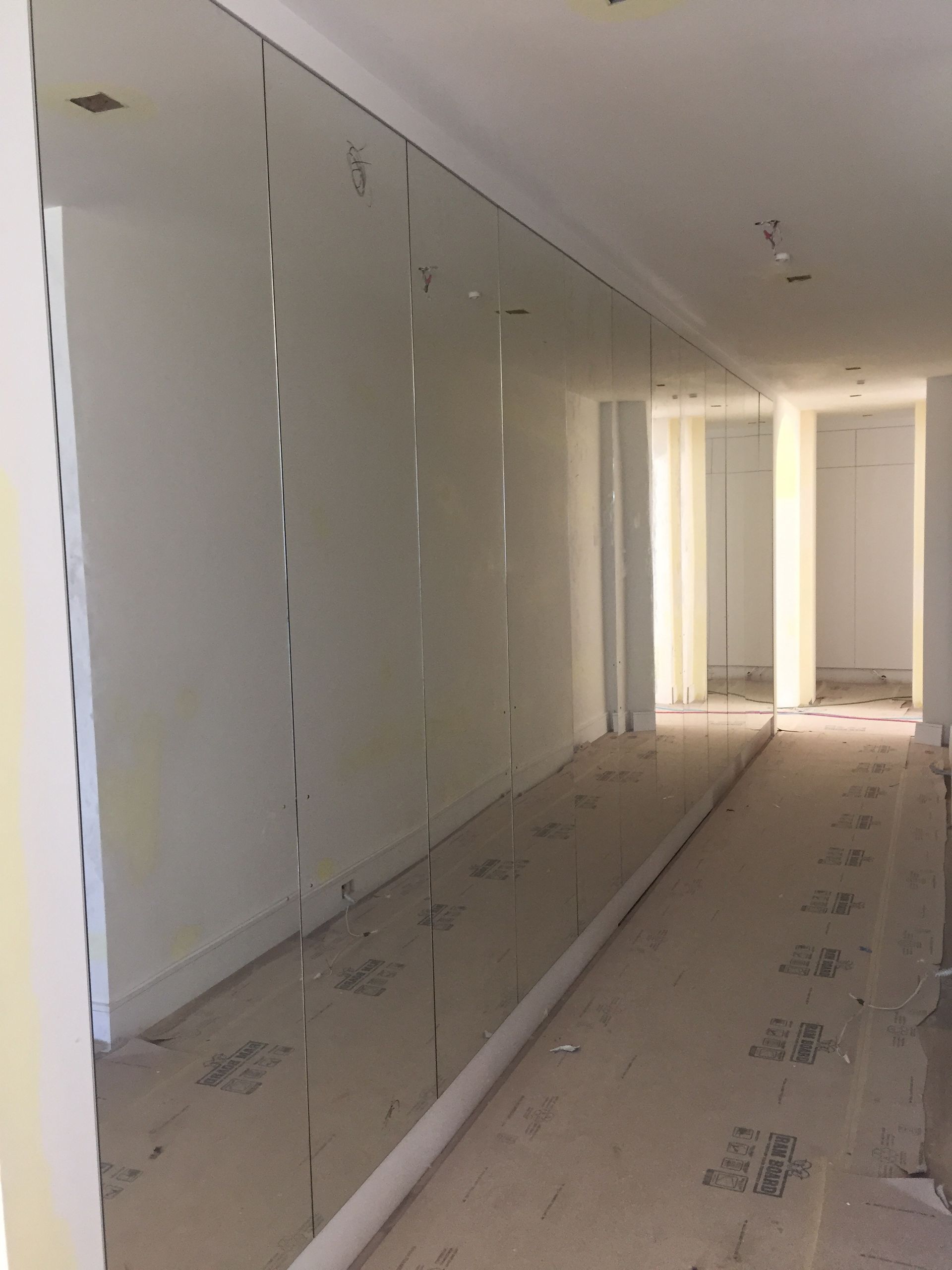 Hallway with mirrored wall and protective floor covering.