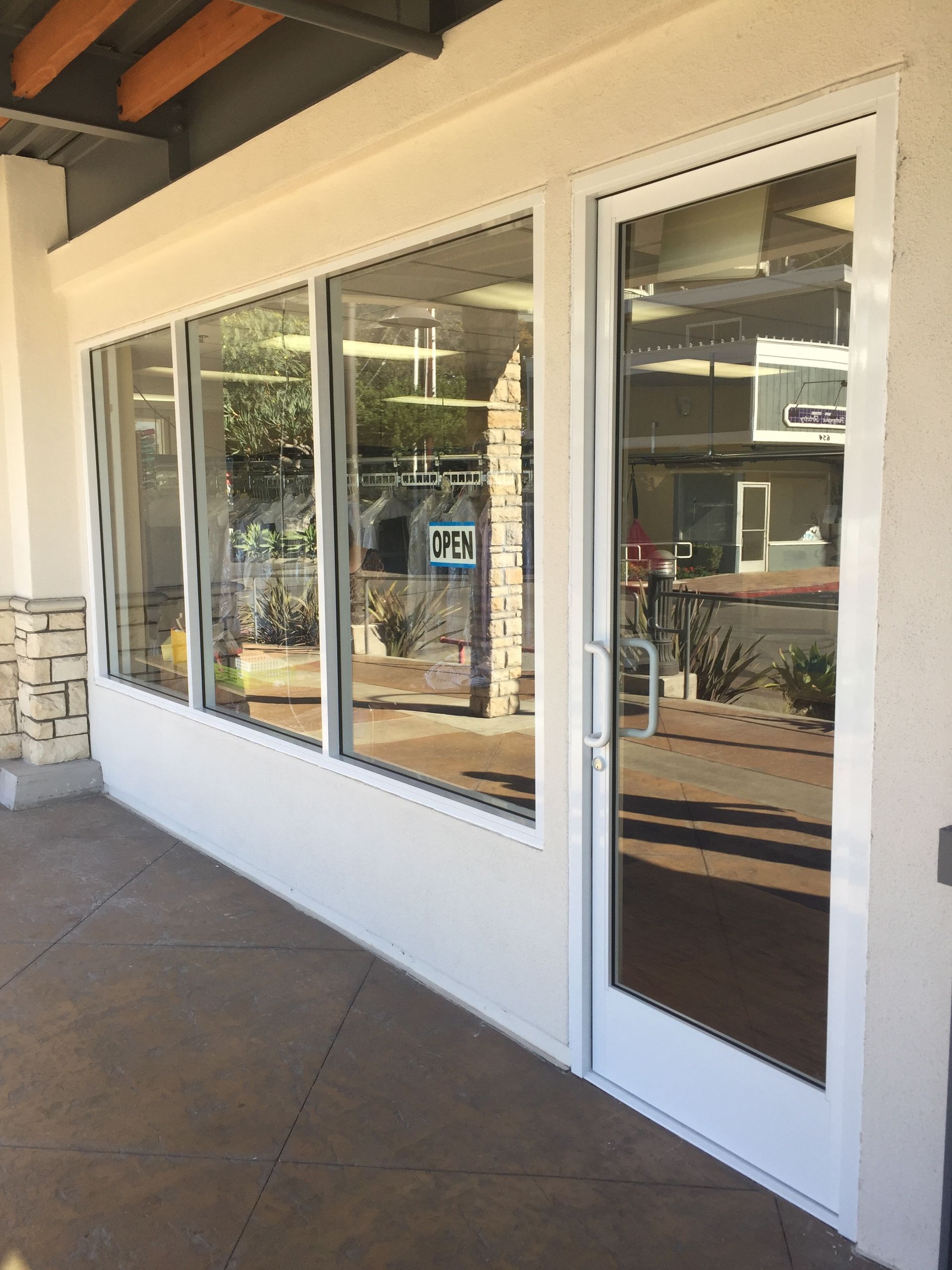 Exterior of a commercial building with glass windows and a door. White trim, neutral colors.