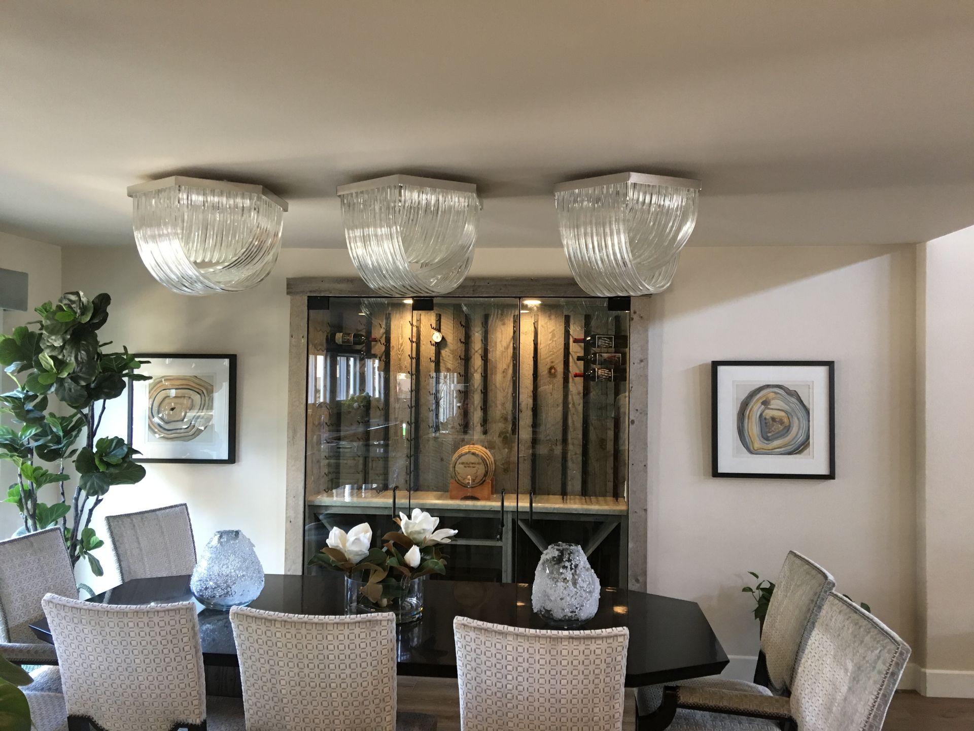 Dining room with dark table, woven chairs, three glass pendant lights, and built-in bar.