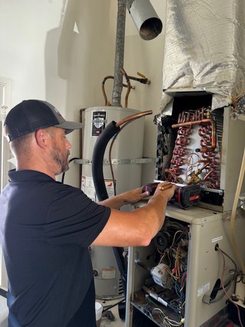 A man is working on a water heater in a room.