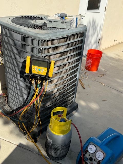 An air conditioner is being serviced on the sidewalk