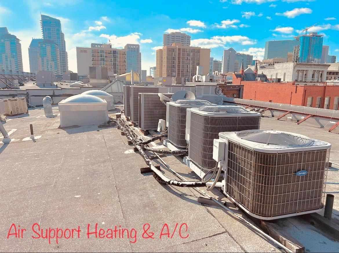 There are a lot of air conditioners on the roof of a building.