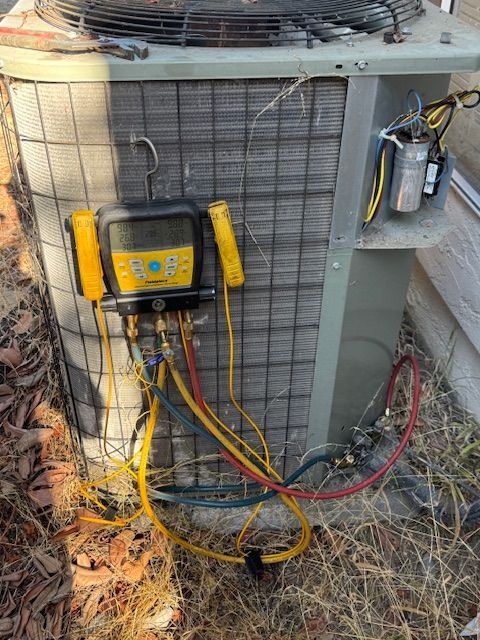 An air conditioner is being serviced with a vacuum gauge attached to it.
