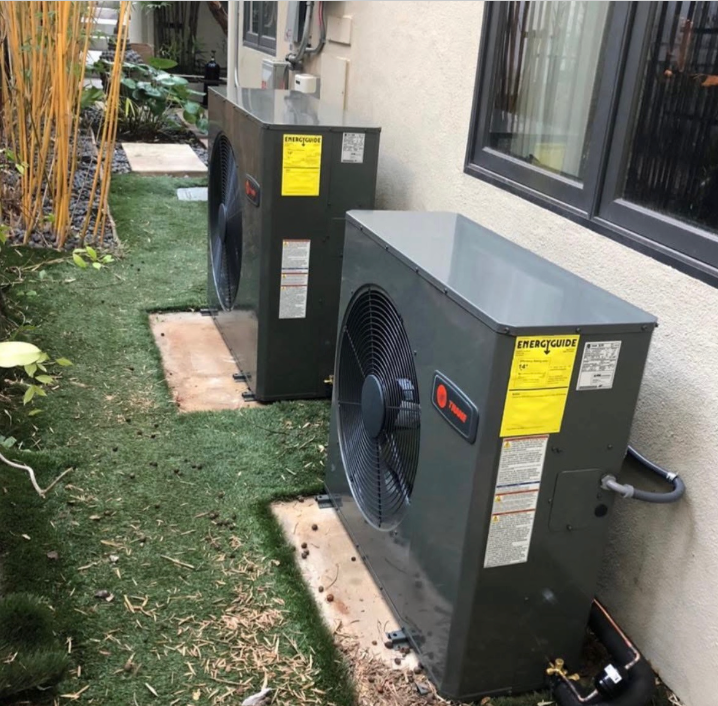 Two air conditioners are sitting on the side of a building