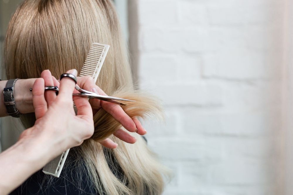 A Woman is Getting Her Hair Cut by a Hairdresser — Hair It Is In Tarrawanna, NSW