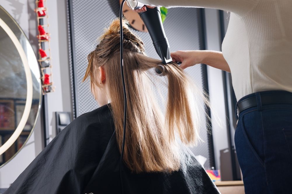 A Woman is Getting Her Hair Blow Dried by a Hairdresser in a Salon — Hair It Is In Fernhill, NSW