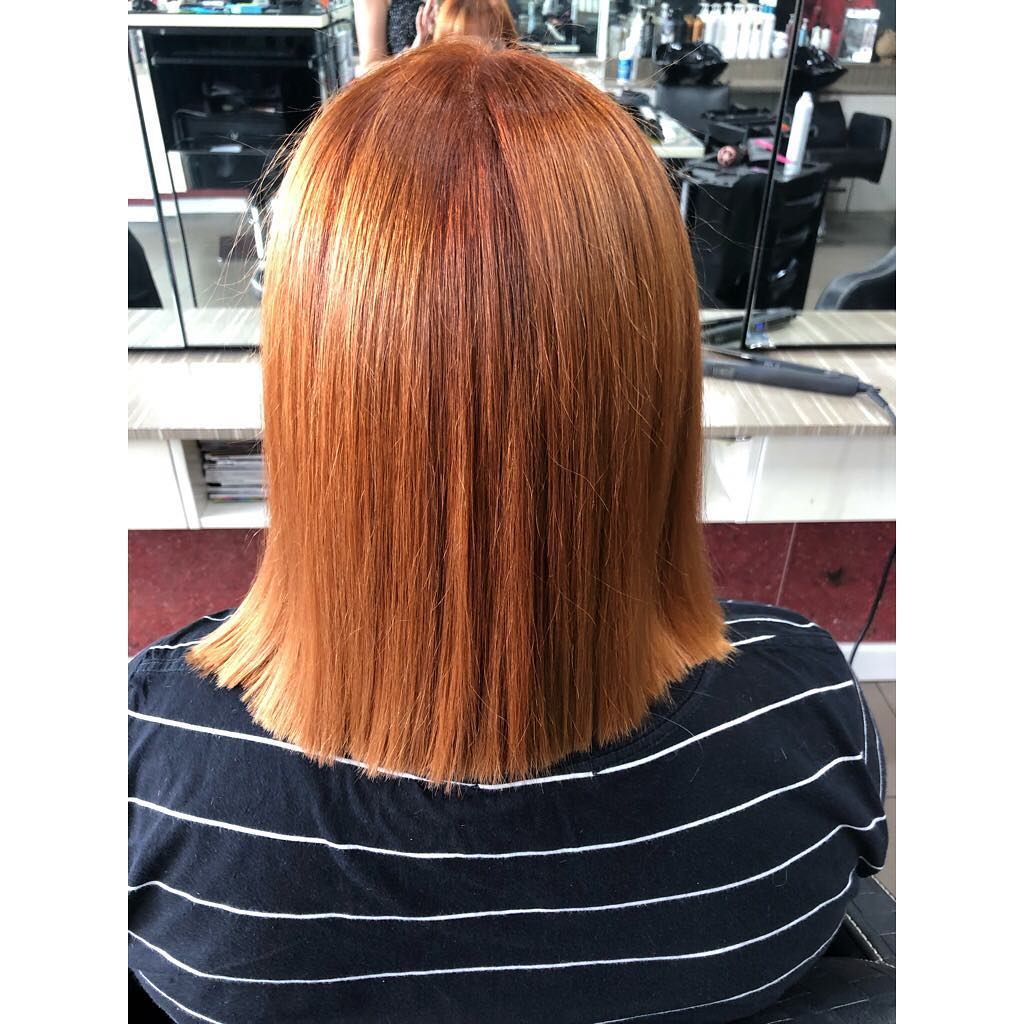 A Woman with Red Hair Is Sitting in A Chair in Front of A Mirror in A Hair Salon — Hair It Is In Balgownie, NSW