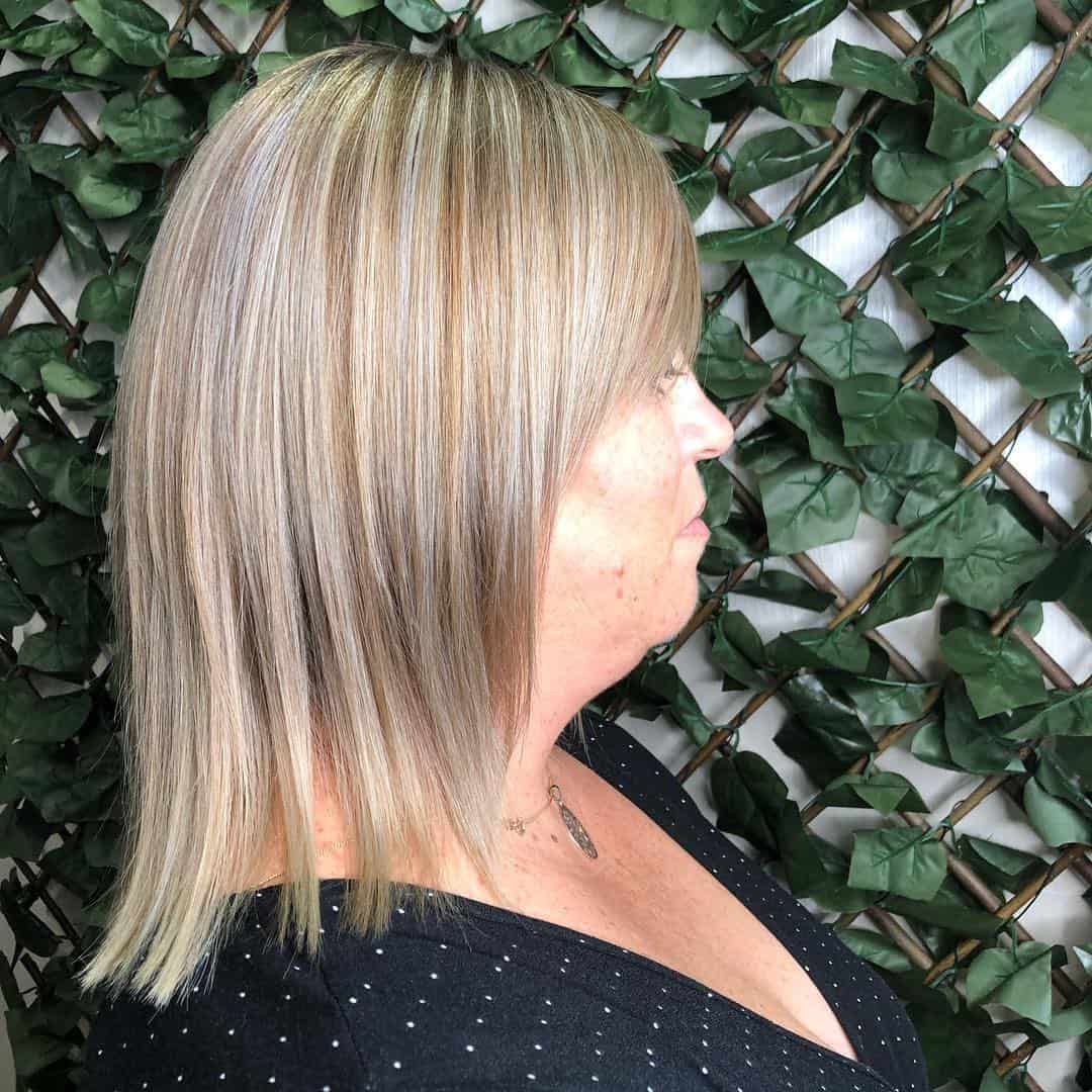 A Woman with Blonde Hair Is Standing in Front of A Green Hedge — Hair It Is In Balgownie, NSW
