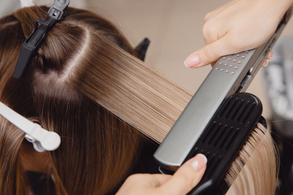 A Woman is Getting Her Hair Straightened by a Hairdresser — Hair It Is In Balgownie, NSW
