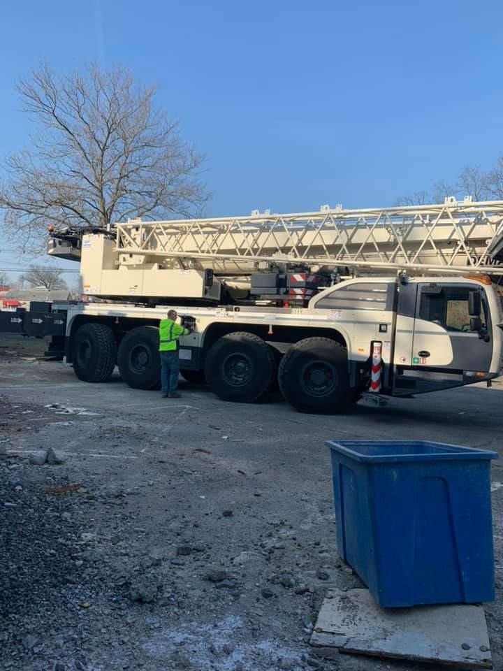 A man is standing next to a large crane in a parking lot.