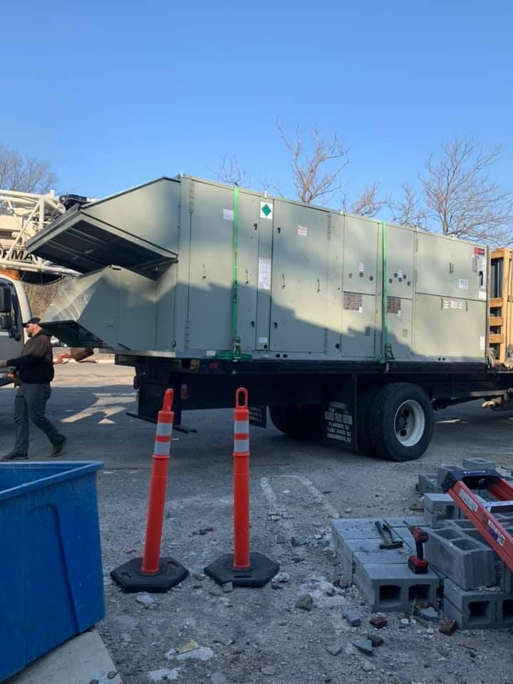 A large air conditioner is being loaded onto a truck.