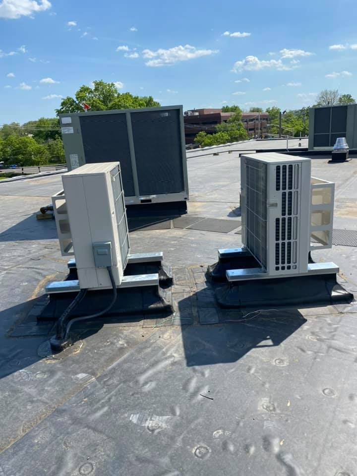 Two air conditioners are sitting on top of a roof.