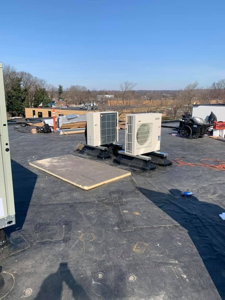 Two air conditioners are sitting on top of a roof.