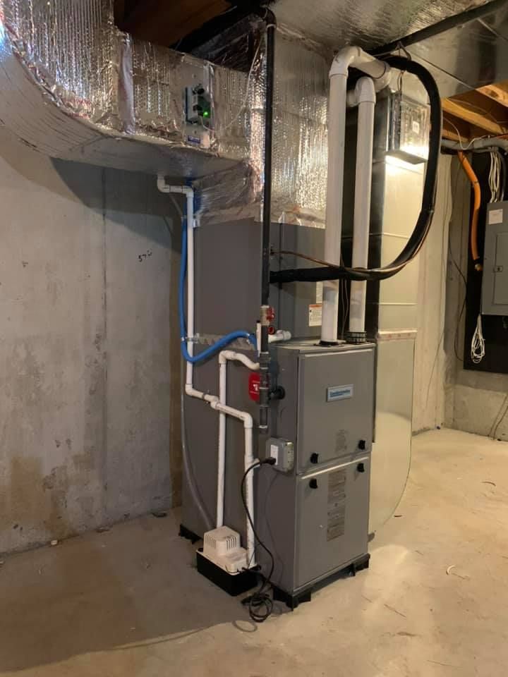 A furnace is sitting in a basement next to a wall.