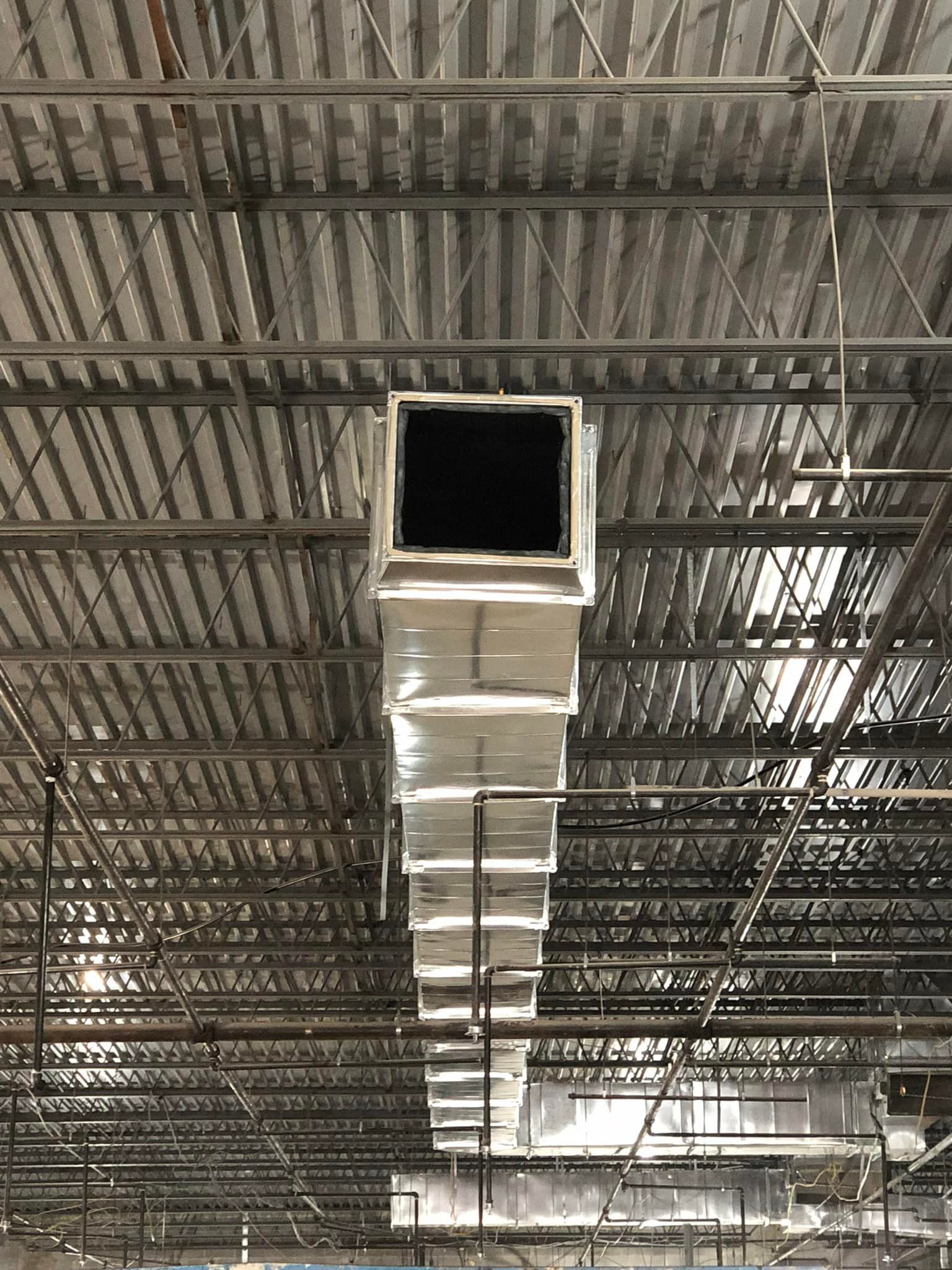 A large air duct is hanging from the ceiling of a building.