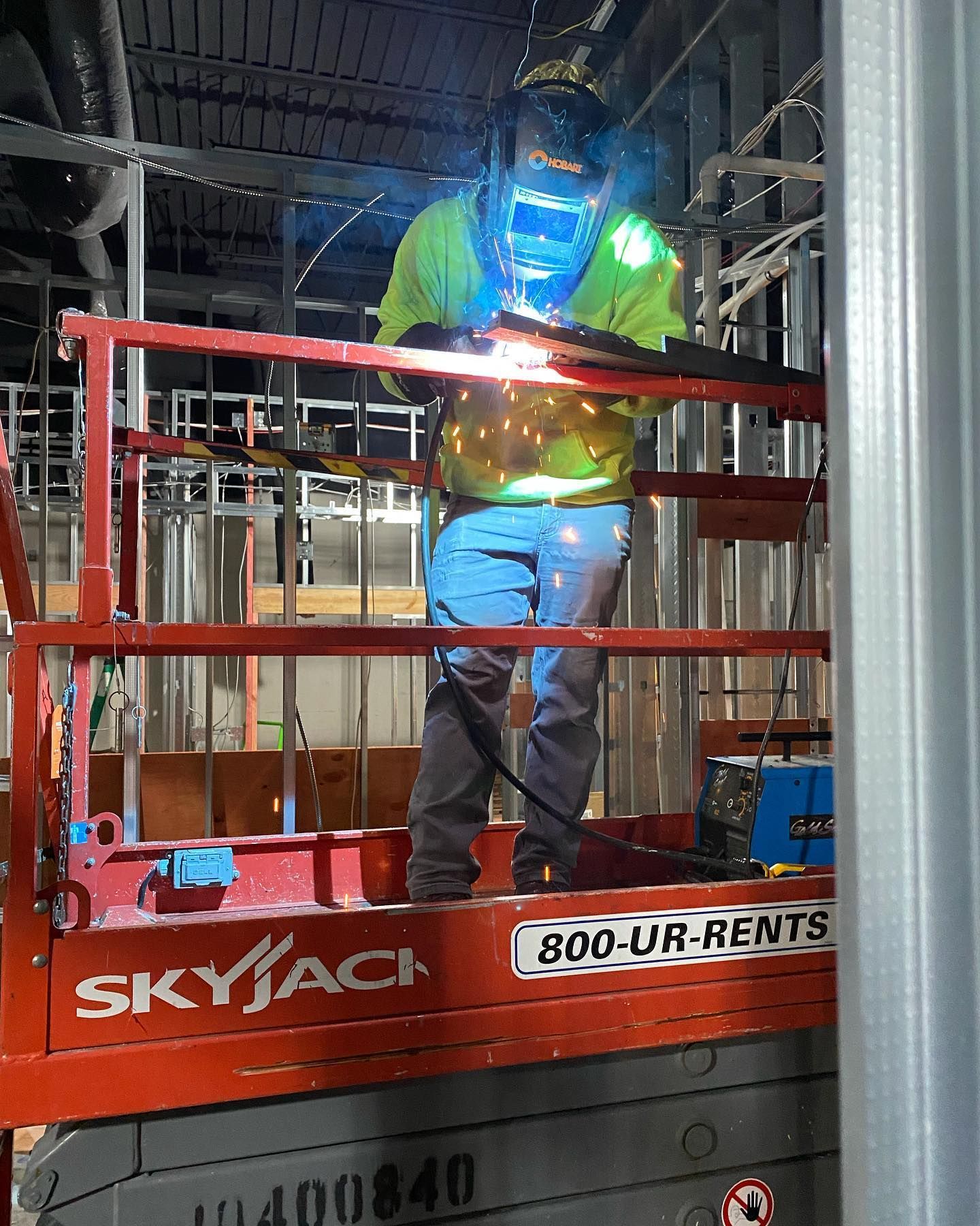 A man is welding on a skyjack platform