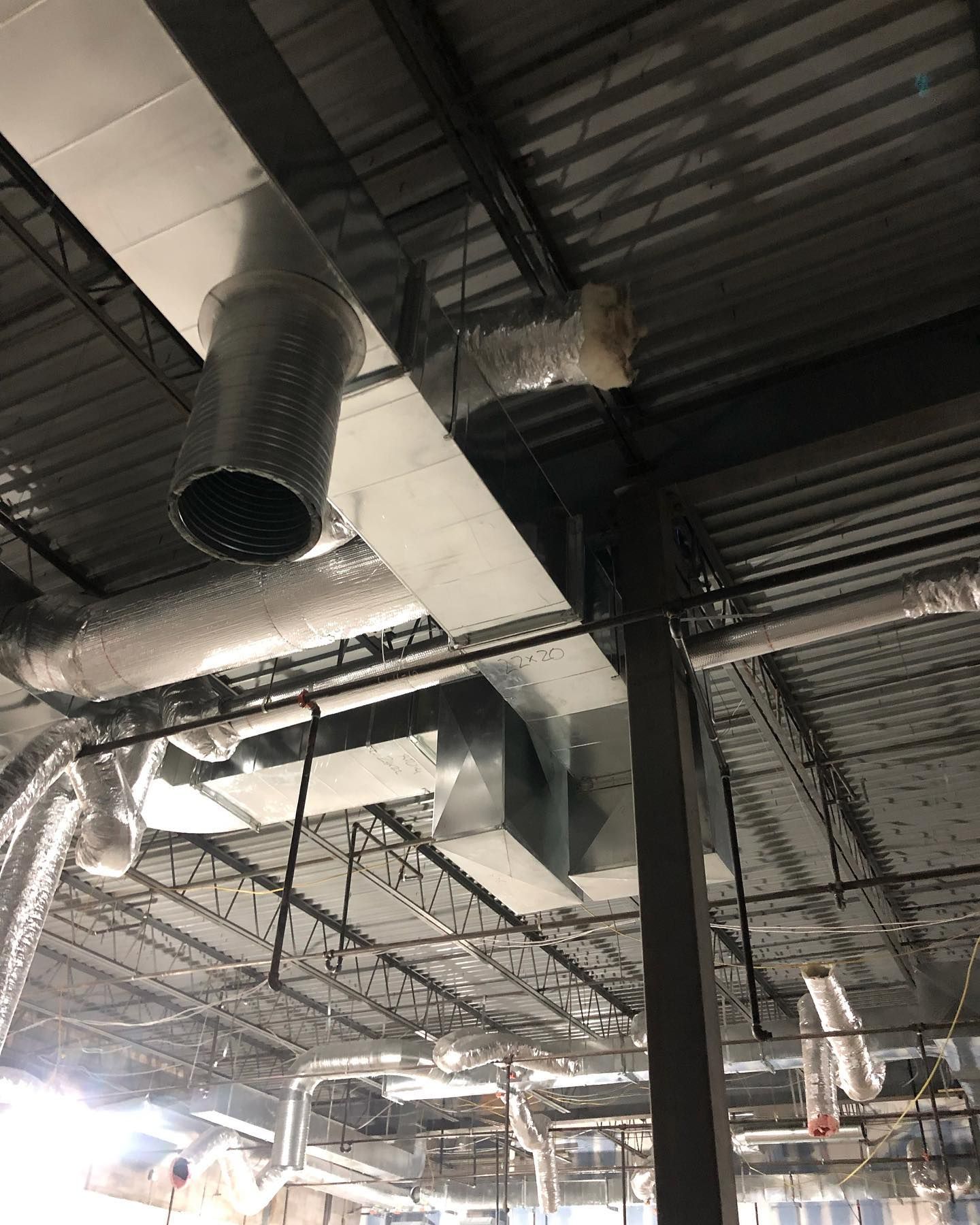 There are a lot of pipes hanging from the ceiling of a building.