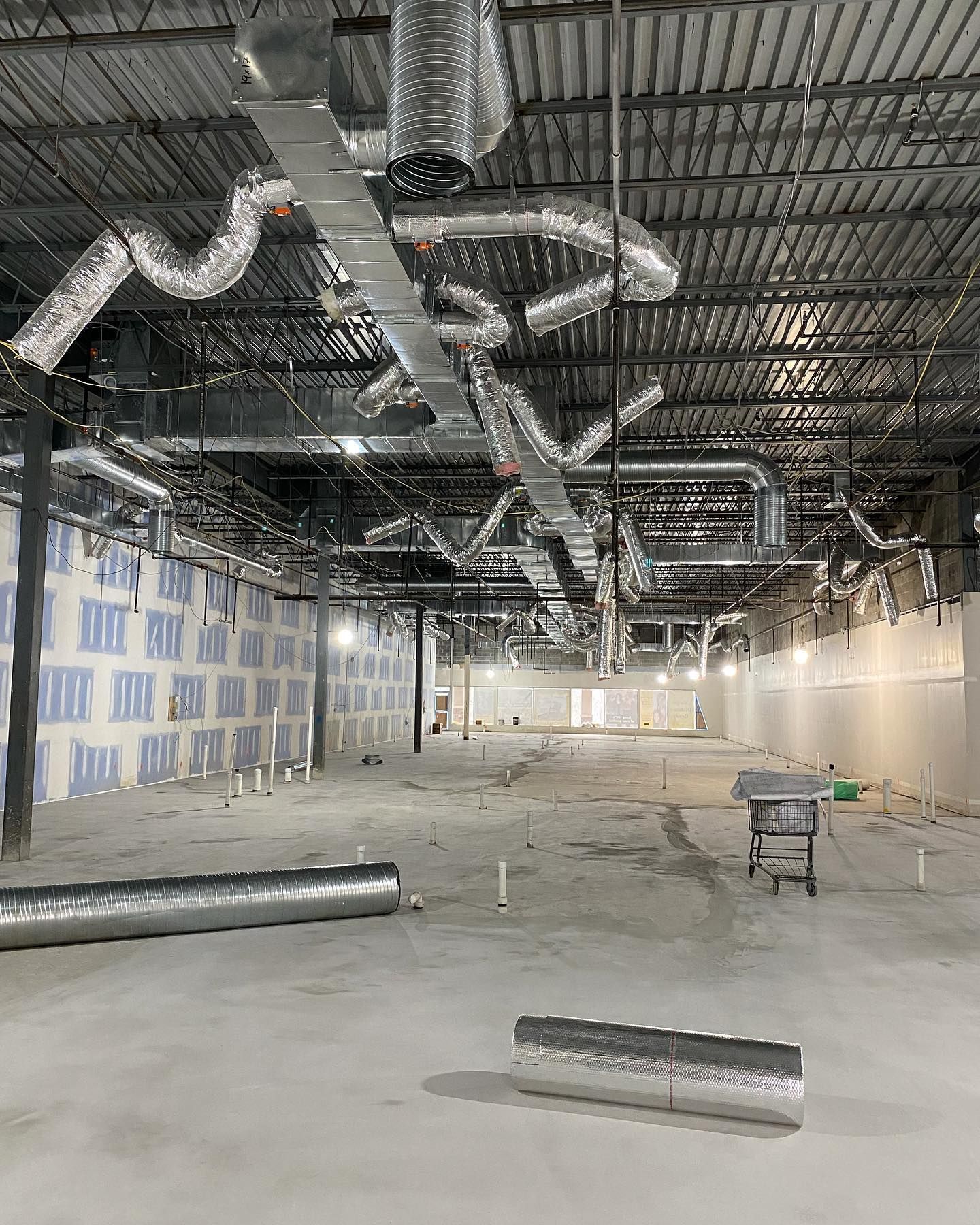A large empty warehouse with a lot of pipes hanging from the ceiling.