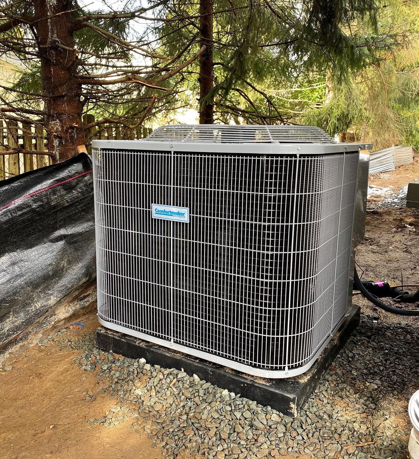 A large air conditioner is sitting on top of a pile of gravel.