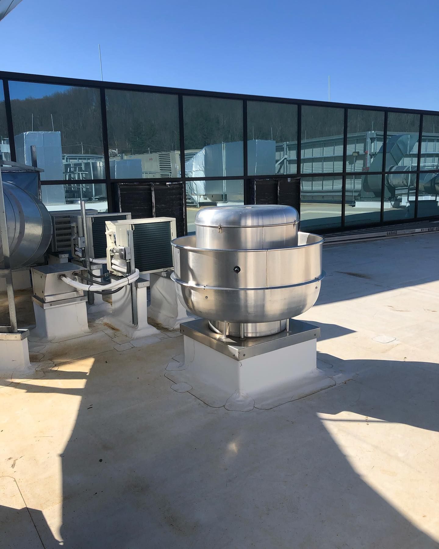 A stainless steel fan is on the roof of a building.