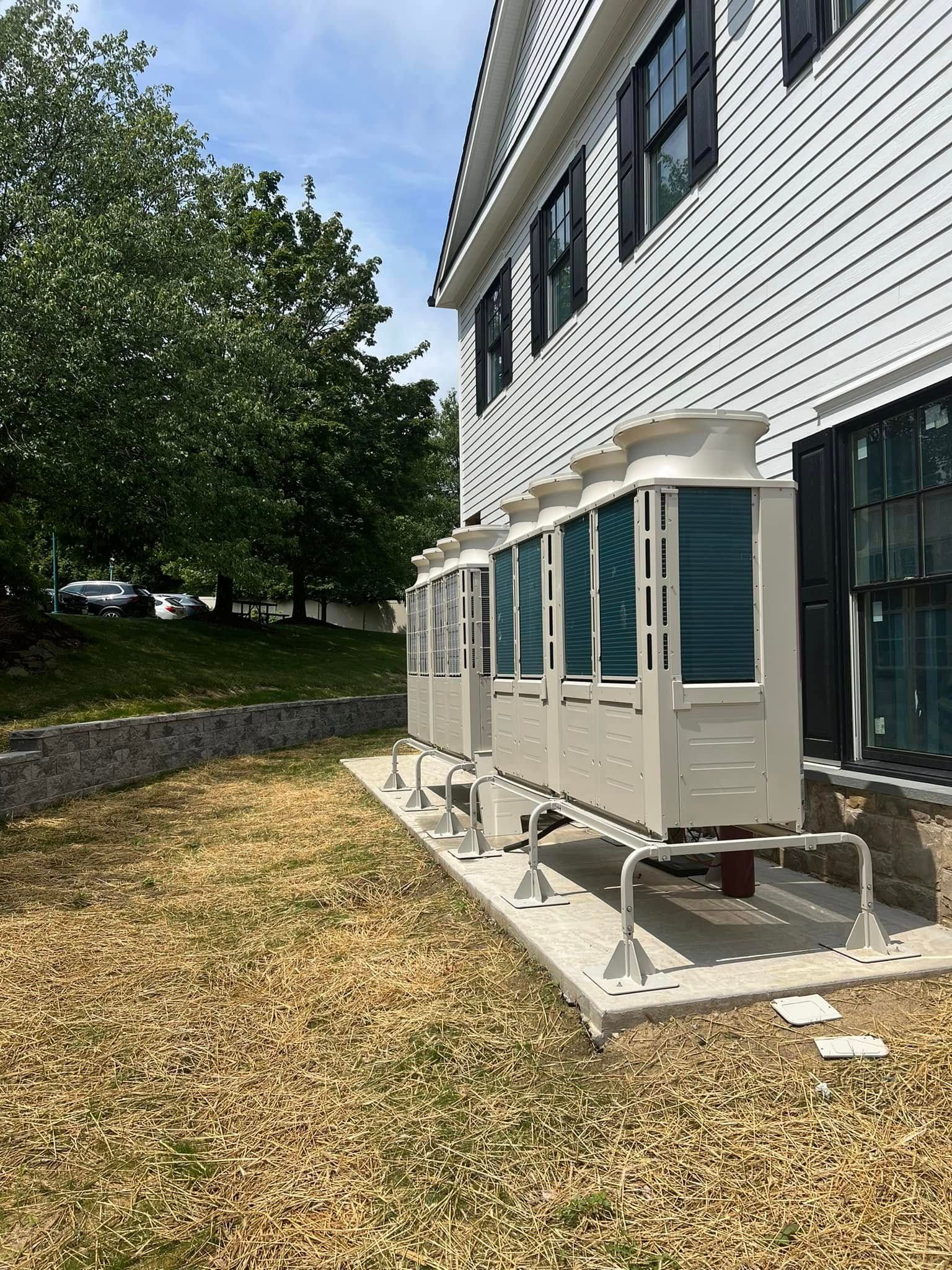 A large white house with a row of air conditioners on the side of it.