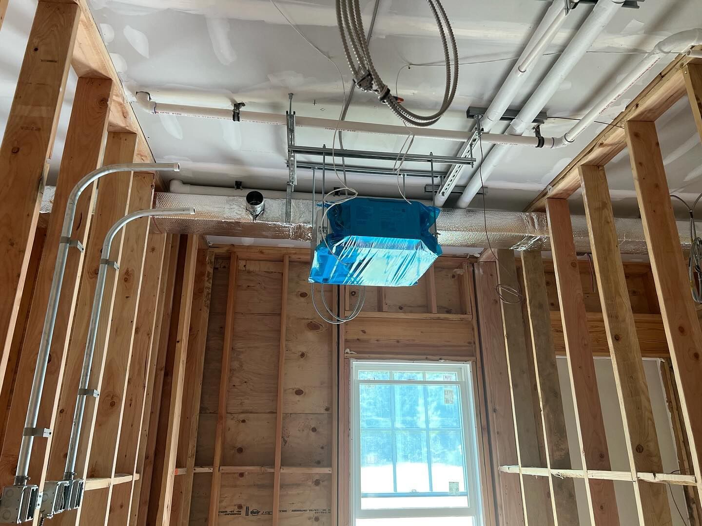 A room in a house under construction with a blue box hanging from the ceiling.