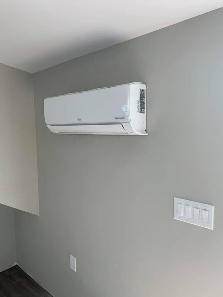 A white air conditioner is hanging on a wall in a room.