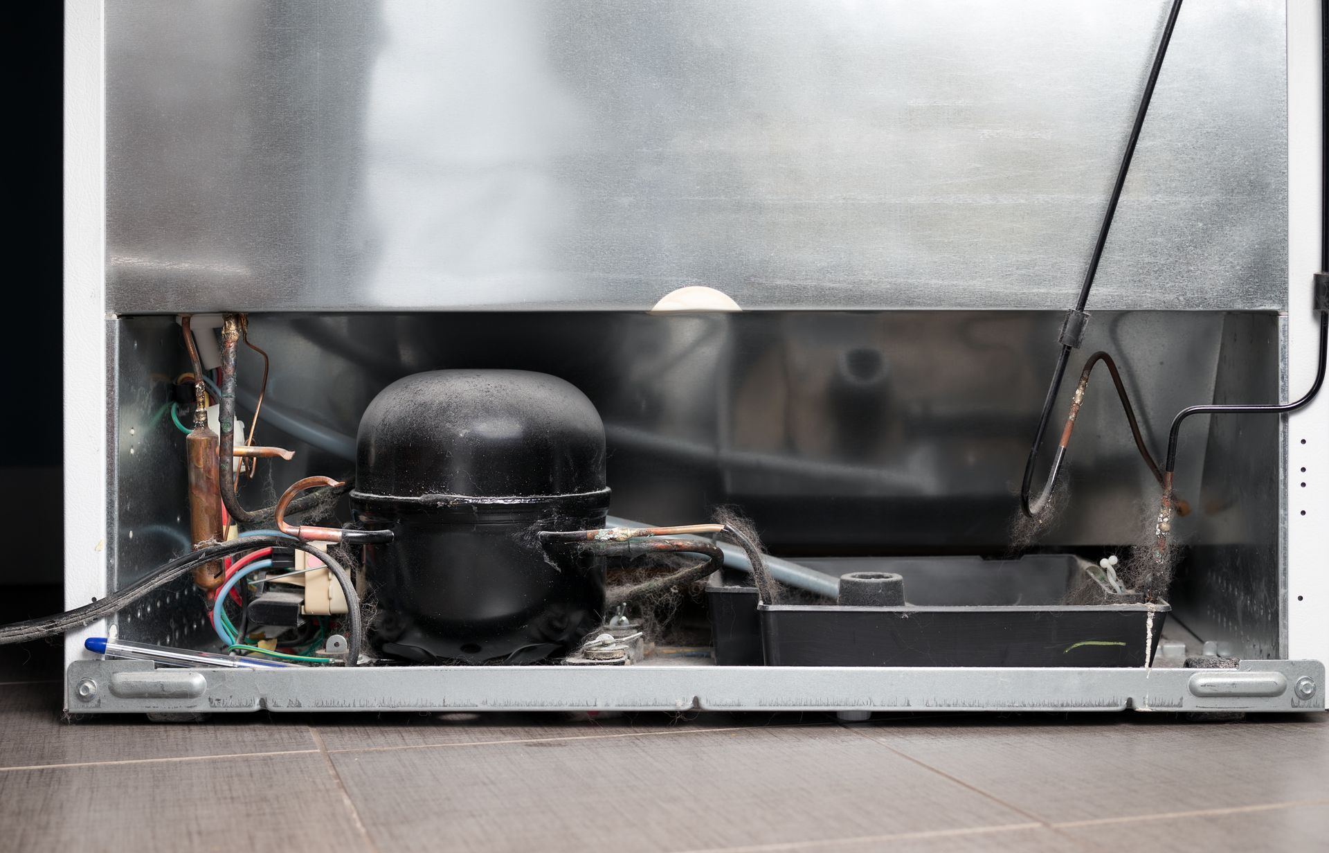 The inside of a refrigerator with the compressor visible.