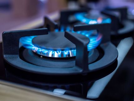 A close up of a gas stove with blue flames coming out of it.