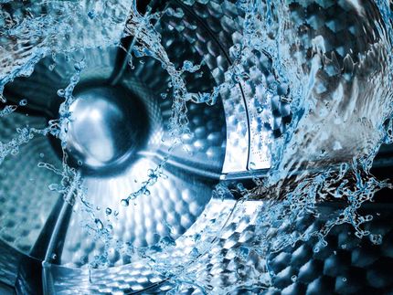 A close up of a washing machine with water splashing out of it.