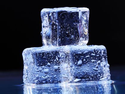 Two ice cubes are stacked on top of each other on a table.